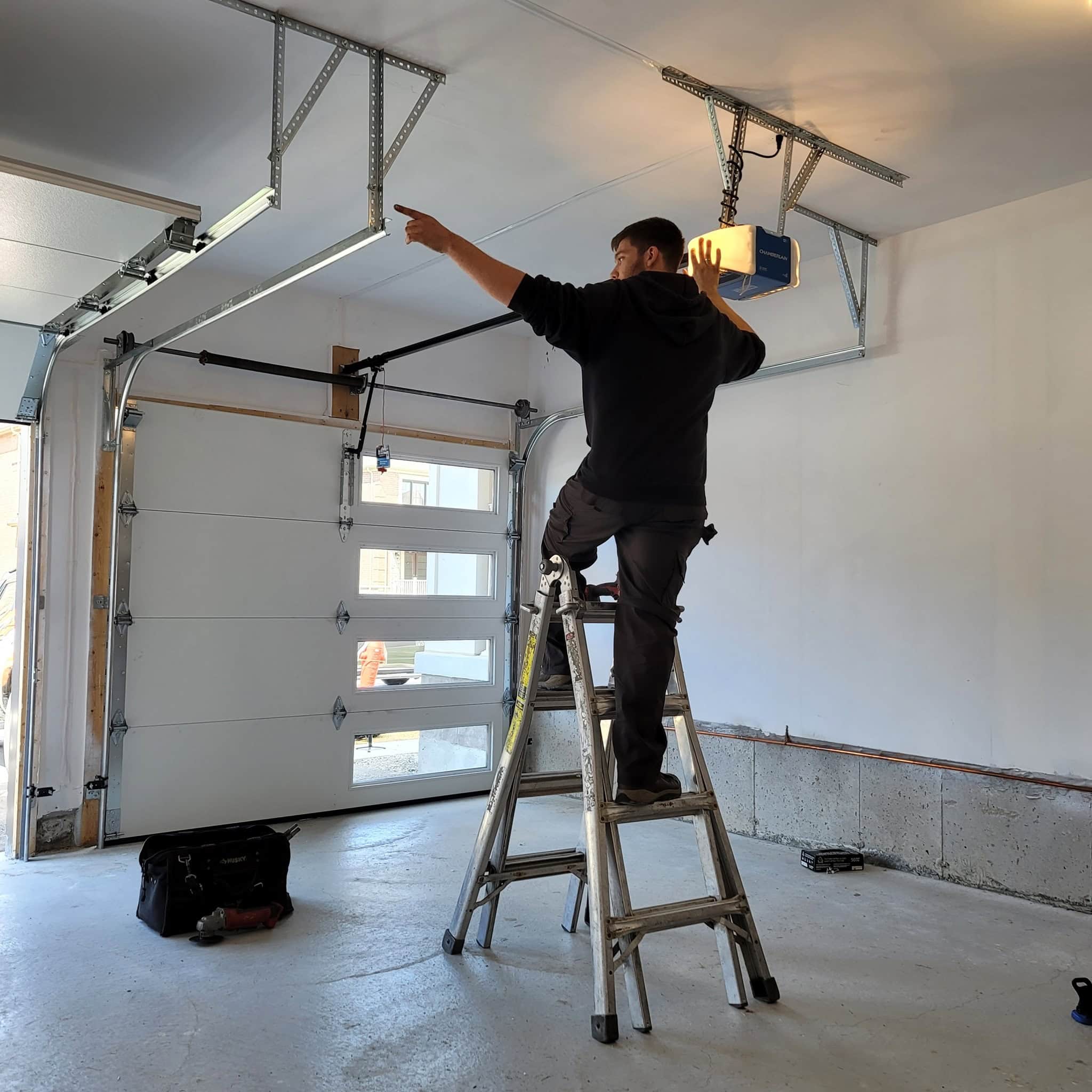 Technician inspecting a garage door opener and track