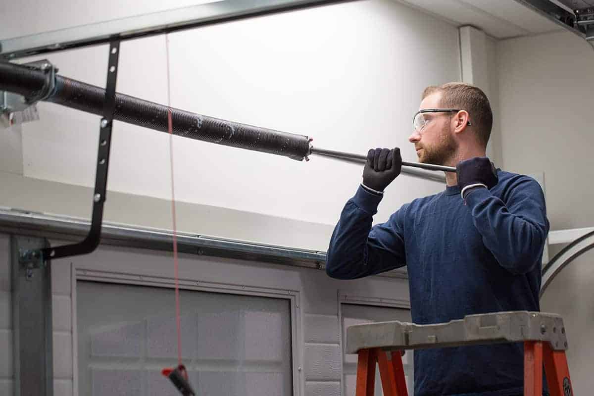 Technician safely working on a garage door torsion spring